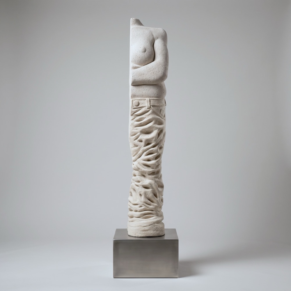 A tall aerated-concrete column. A torso at the top gives way to deeply crumpled folds of fabric sagging down the length of the column.